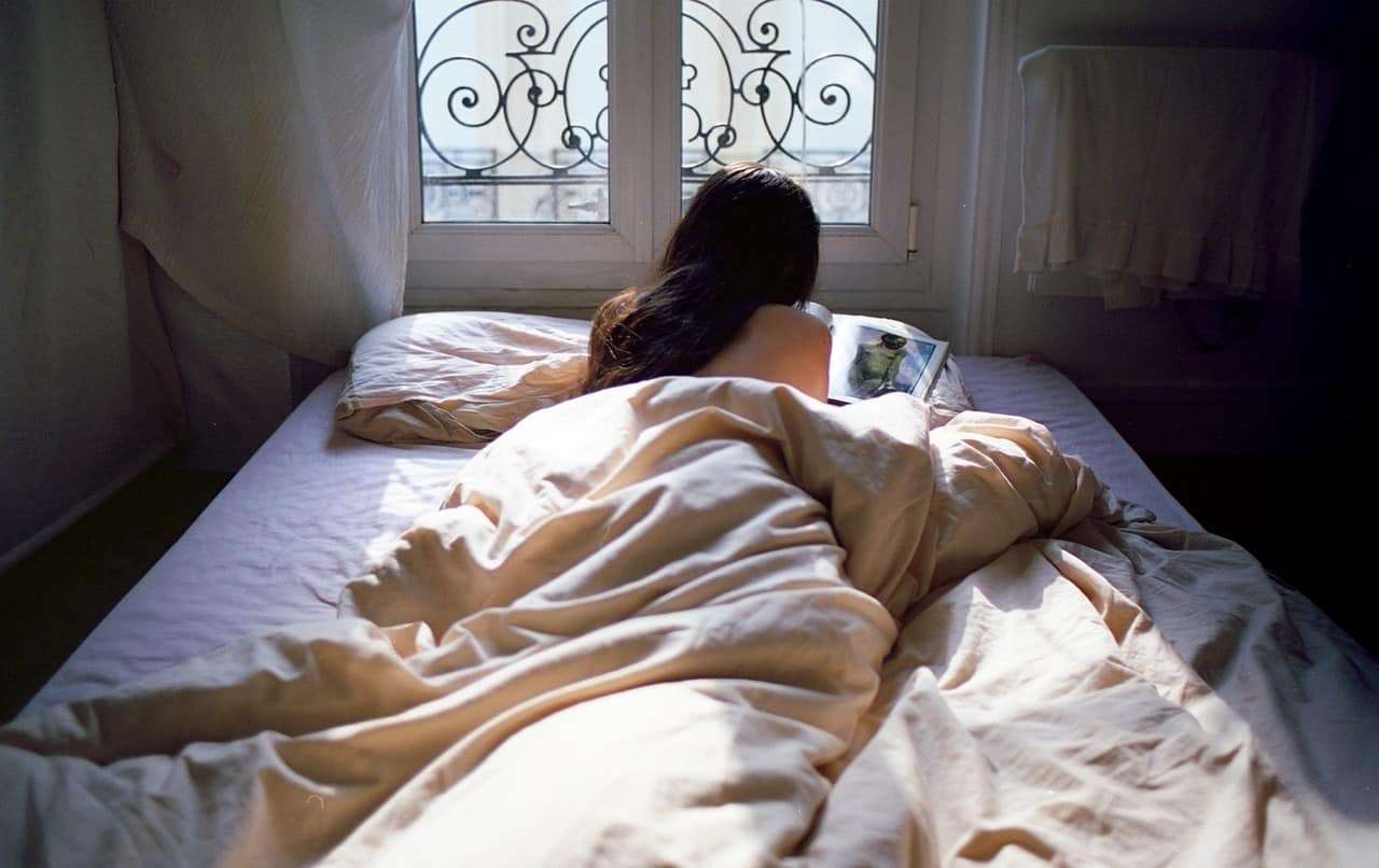Одинокая голая женщина  на большой кровати 